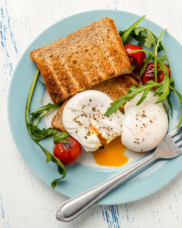two poached eggs with a salad on a blue plate.
